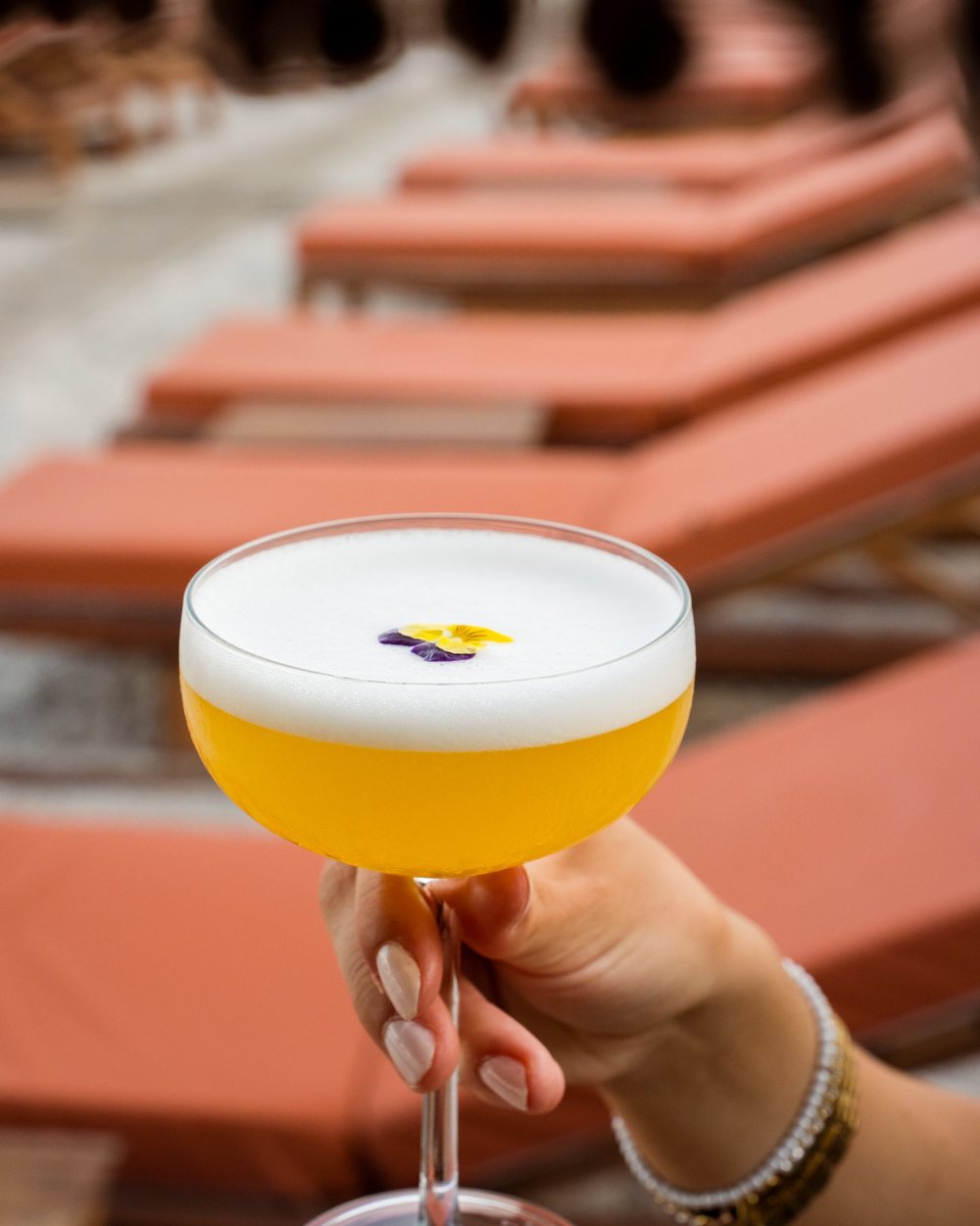 Cocktail held over orange sun loungers at a beach bar in Lefkada