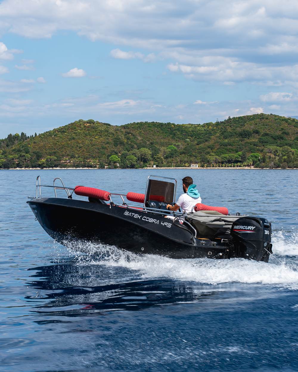 Speedboat cutting through the sea near a green island in Lefkada